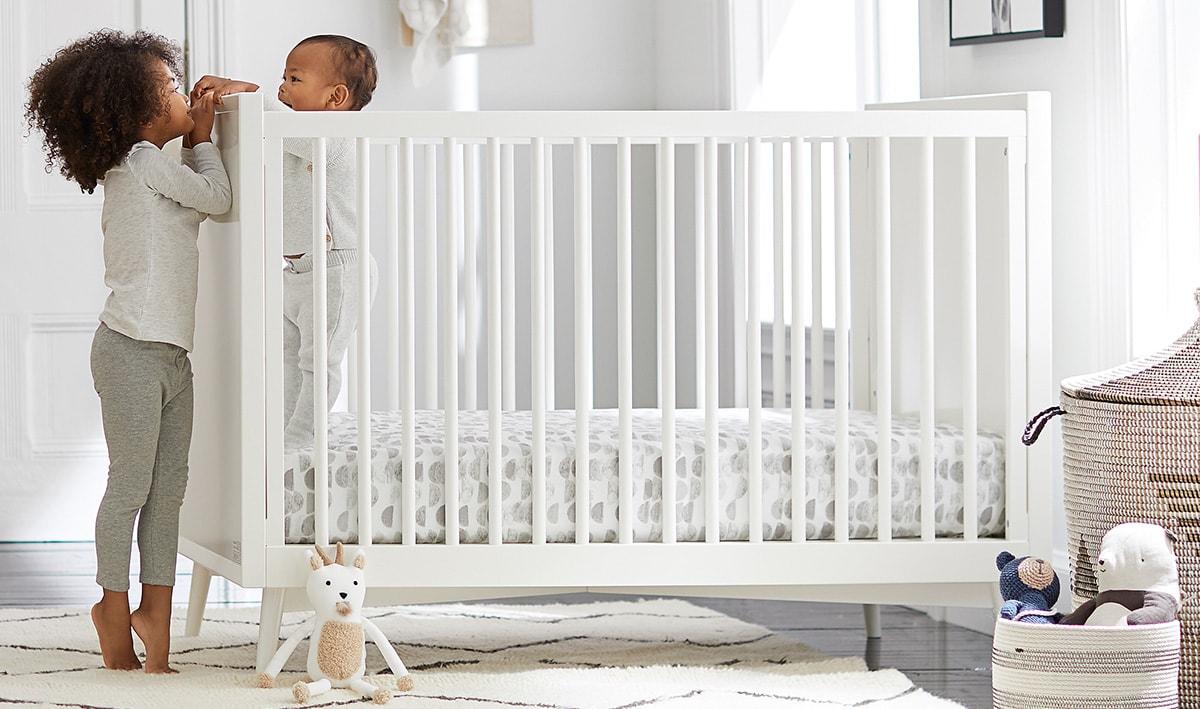 Baby in his cot being greeted by his older sister